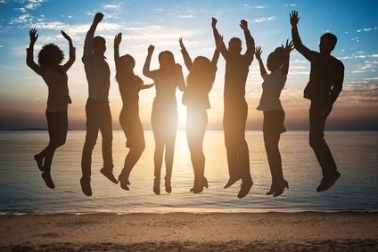 Gruppe springt bei Sonnenuntergang am Strand in die Luft