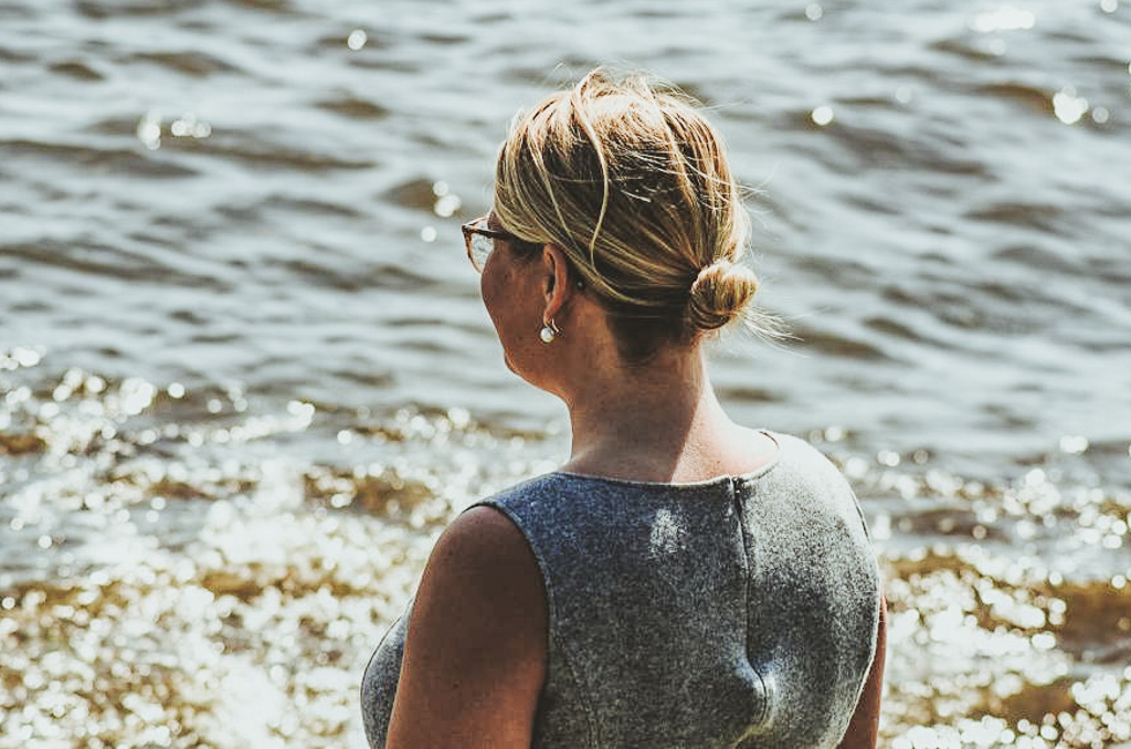 Frau mit Brille blickt auf das glitzernde Meer